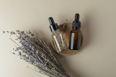 A face serum or oil in a brown dropper bottle standing on a beige table background 