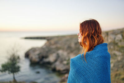 Woman looking at sea against sky during sunset