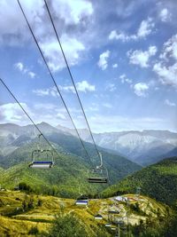 Overhead cable car over mountains against sky