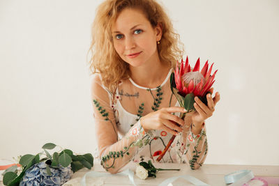 Portrait of young woman holding flower at table