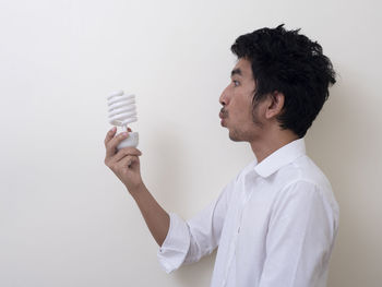 Side view of young man standing against white background