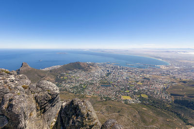 Aerial view of sea and cityscape against blue sky