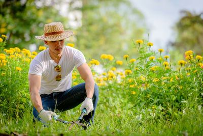 Low angle view of farmer working using pruning shears on field