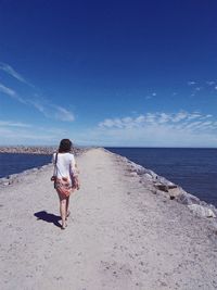 Rear view of woman on beach against sky