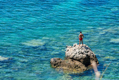 Man standing on rock by sea