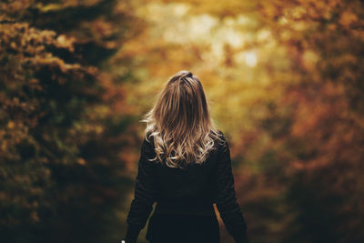 Rear view of woman standing against trees