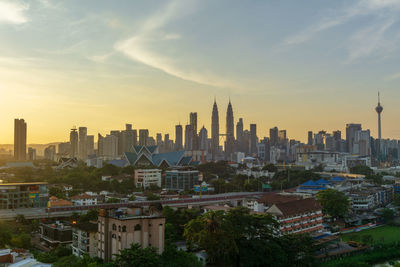 Modern buildings in city against sky during sunset
