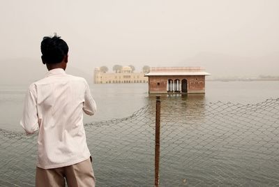 Rear view of man looking at sea against sky