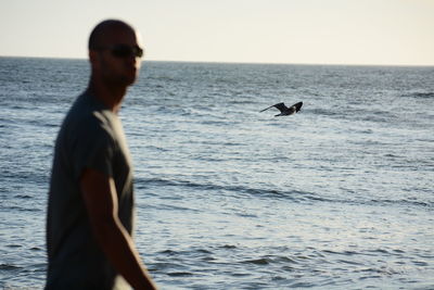 Man swimming in sea against clear sky