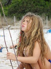 Girl looking up while crouching at beach