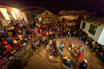 High angle view of people on street amidst buildings at night