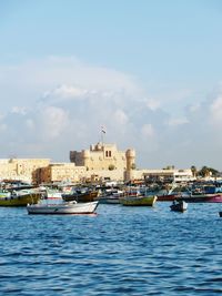 Boats in sea against buildings in city