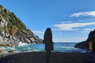 Rear view of woman looking at sea shore against sky