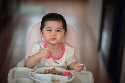 Cute baby girl eating food at home