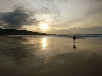 Silhouette person standing on beach against sky during sunset