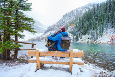 Rear view of man sitting on snow covered landscape