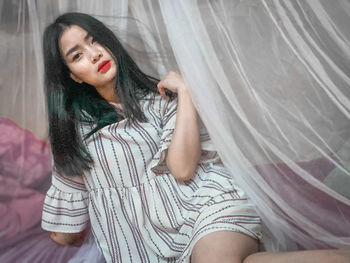 Beautiful young woman sitting in curtain