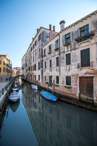 Boats moored on canal amidst buildings