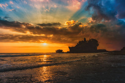 Scenic view of sea against dramatic sky during sunset