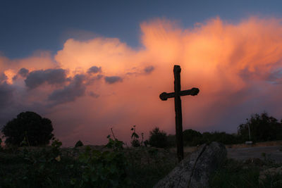 Scenic view of landscape against cloudy sky at sunset