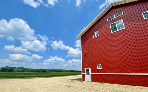 Barn on field by building against sky