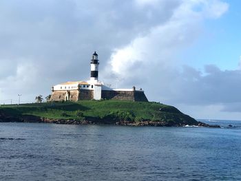 Lighthouse by sea against sky