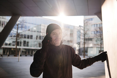 Man talking on phone under bridge during sunny day