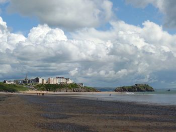 Scenic view of beach by buildings against sky