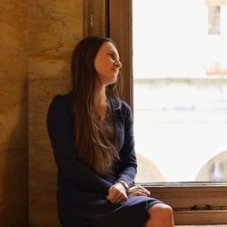 Thoughtful woman sitting by window at home