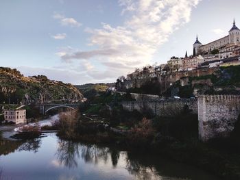 Arch bridge over river against buildings