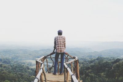 Rear view of man looking at mountain against sky