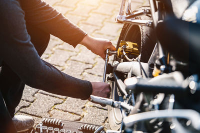 Low section of mechanic repairing motorcycle on street