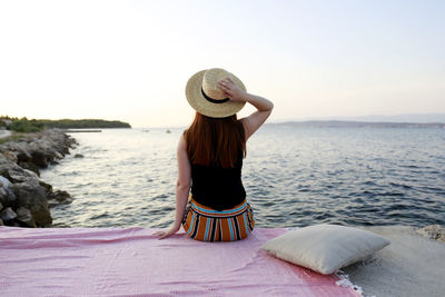 Rear view of woman wearing hat looking at sea