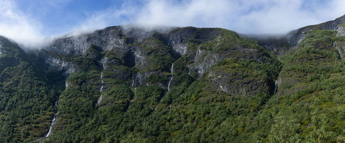 Low angle view of mountains with waterfalls against sky