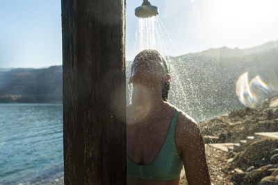 Woman taking shower while standing against sky