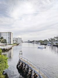 Bridge over river by buildings in city against sky