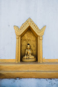 Buddha statue against wall of building