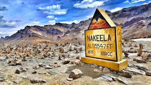 Information sign on rocky mountains against sky