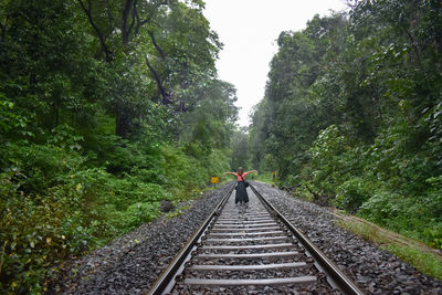 Rear view of woman walking on railroad track