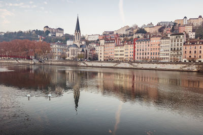 Saone river by buildings and saint georges church in lyon city against sky