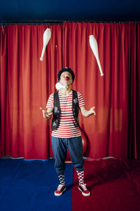 Male performer juggling pins while performing in circus