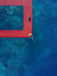 Man sitting on red pier over sea at thulusdhoo island in kaafu atoll, maldives