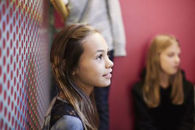 Thoughtful girl looking away with friends in background at middle school