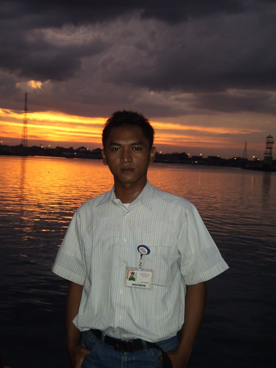 sky, water, sunset, cloud - sky, lifestyles, standing, leisure activity, casual clothing, looking at camera, waist up, three quarter length, sea, cloud, person, dusk, portrait, cloudy, lake