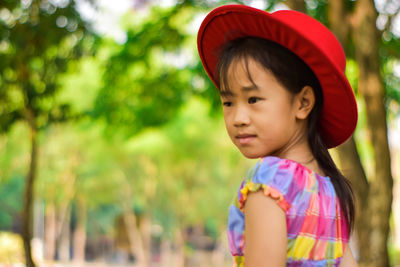 Blurred little girl wear red hat in a summer green park.