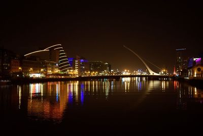 Illuminated bridge over river in city at night