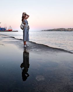 Woman standing on beach against sky during sunset