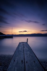 Pier over lake against sky during sunset