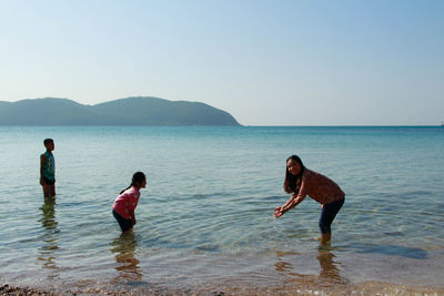 Man and woman in sea against clear sky