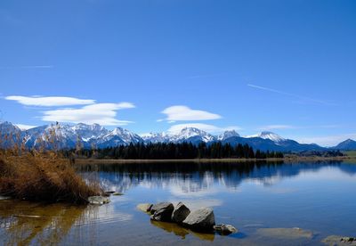 Scenic view of lake by mountains against blue sky